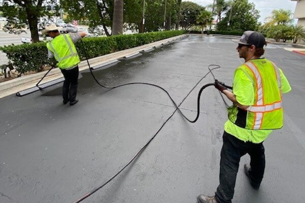 Team spraying sealcoating on a parking lot