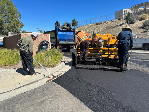 Paving crew installing asphalt drive apron