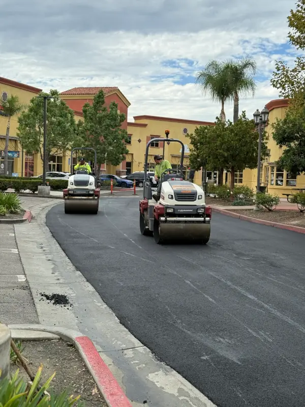 two rollers compacting asphalt on a parking lot